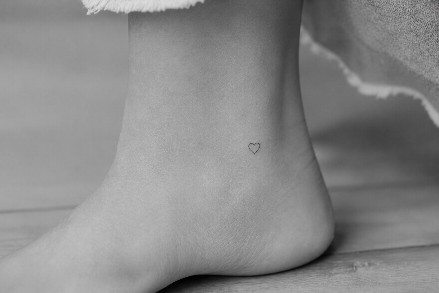 Tatuaje minimalista de corazón en el tobillo