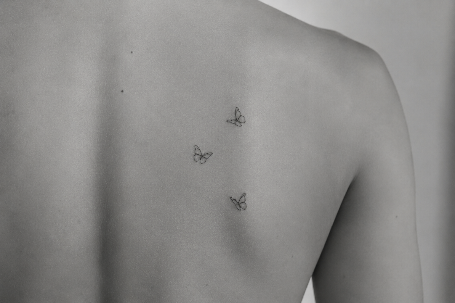 Tatuaje de tres mariposas finas en la espalda